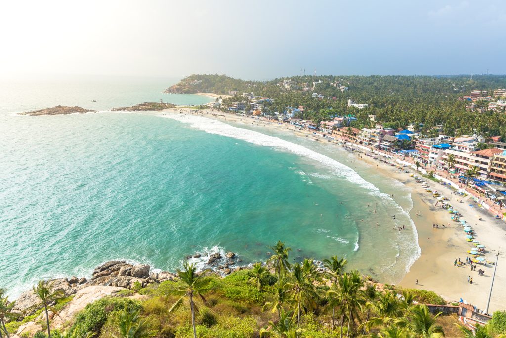 Aerial view of tourists in the turquoise waters of Lighthouse beach at Kovalam, Trivandrum.